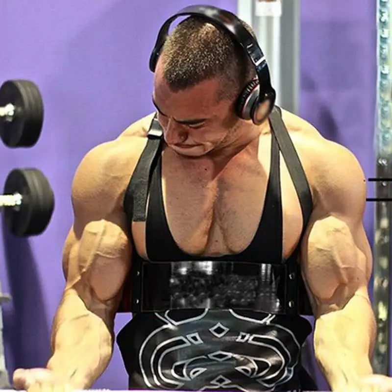 A muscular person with headphones is performing an exercise in a gym, wearing a black tank top and using the JB Muscle™ Arm Blaster: Bicep Isolator from JB Muscle for optimal bicep growth.