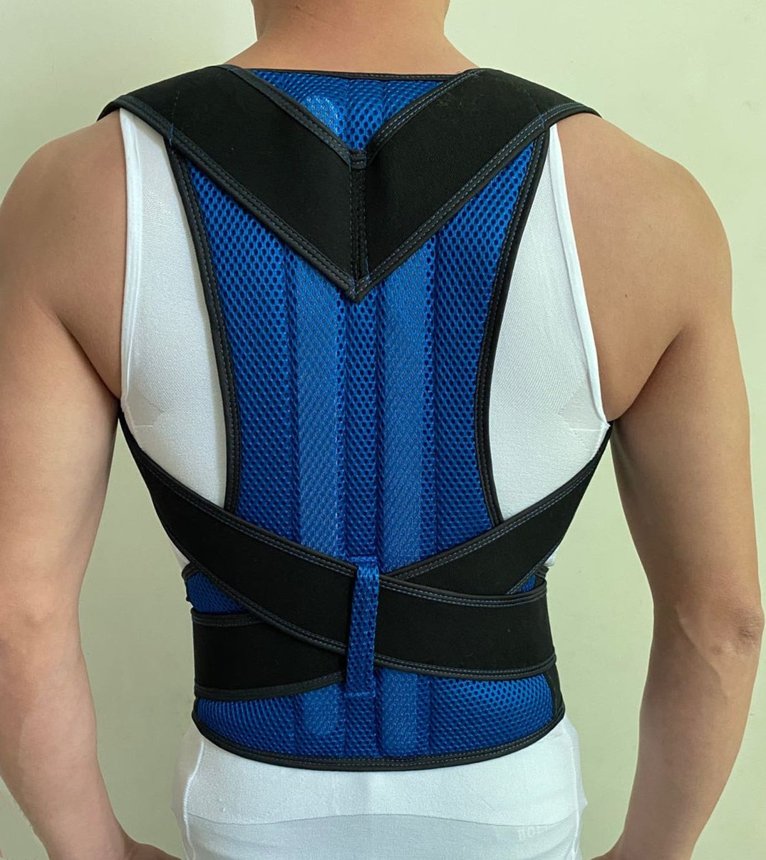 A person wearing a blue and black JB Muscle™ Adjustable Posture Corrector Brace | Back Support Harness over a white tank top, viewed from the back, ensuring optimal back and shoulder support.