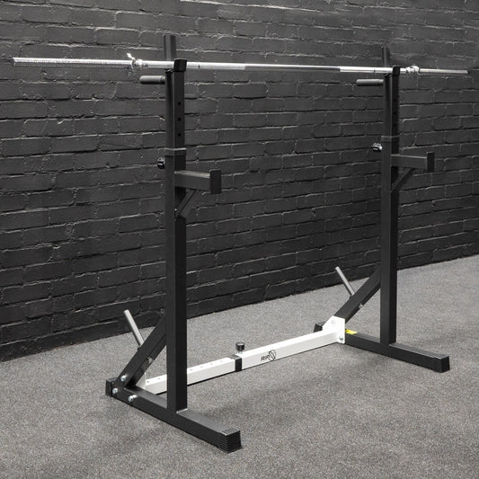 The JB Muscle RIP X Standard Barbell 1" Diameter with Spinlock Collars is set up on a carpeted floor against a black brick wall in a squat rack.