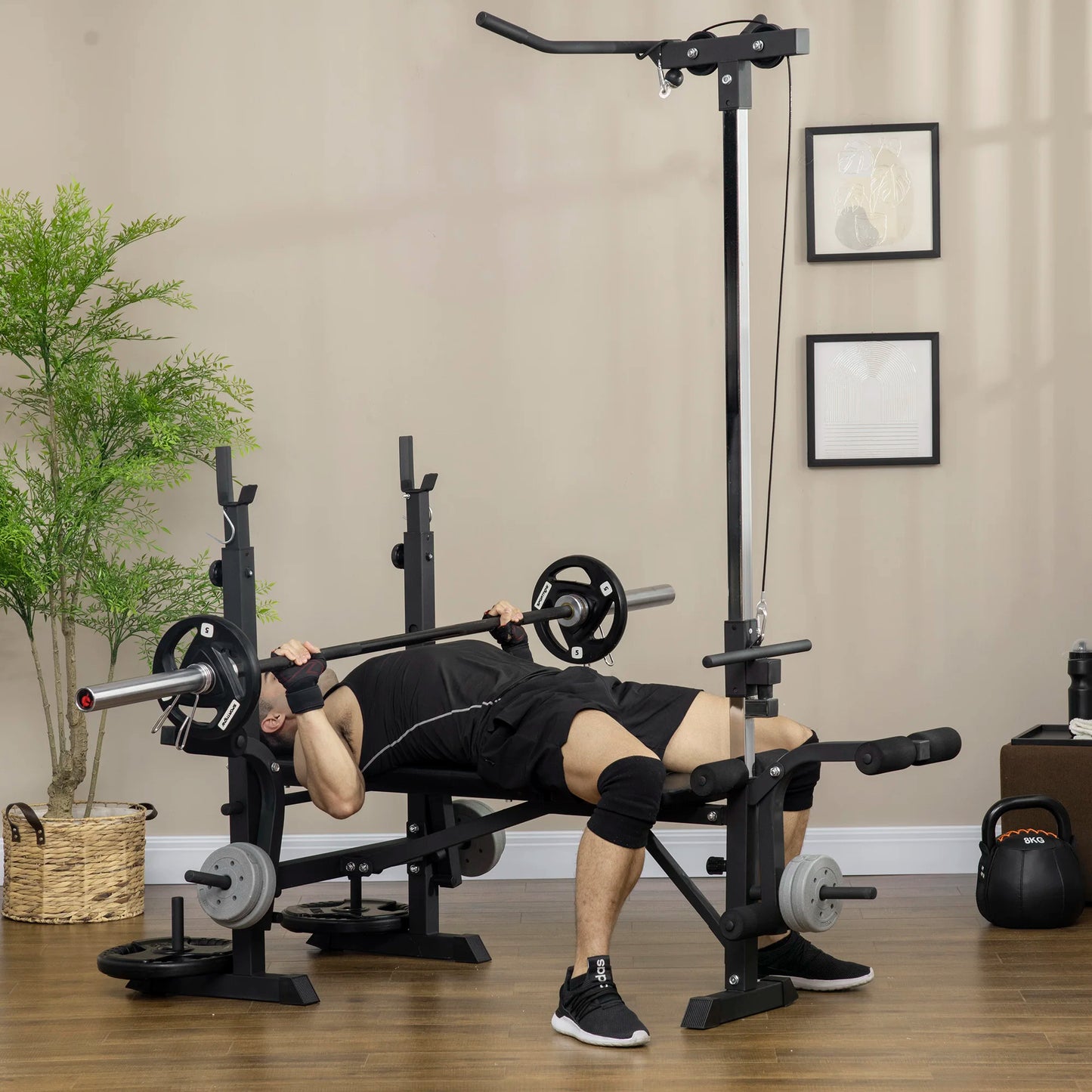 A person trains at home with the JB Muscle HOMCOM Multi Station Exercise Bench, lifting a barbell and using features like butterfly curl, lat pulldown, and leg curl on a wooden floor amid gym equipment.