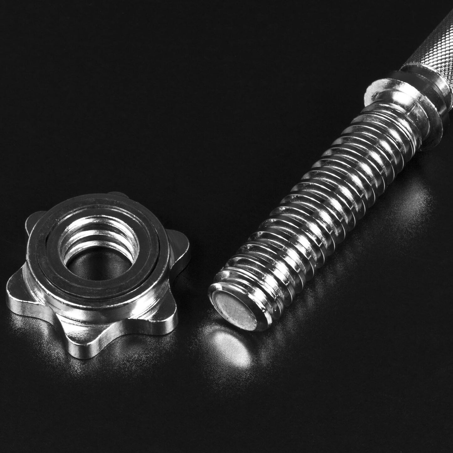 A close-up of a JB Muscle Spinlock DUMBBELL BARS Standard 1 Inch Plates Weightlifting Bar & Collars Set handle, with a threaded collar nut beside it, resting on a black surface.